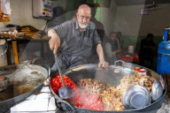 Man cooking food in a giant pod, Bird street, Kabul, Afghanistan