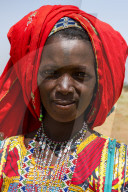 Colourful dressed woman travels with a caravan of Peul nomads and their animals in the Sahel of Niger