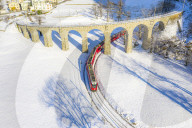 Bernina Express passes under the helical viaduct of Brusio. Valposchiavo, Canton of Graubunden, Switzerland, Europe.