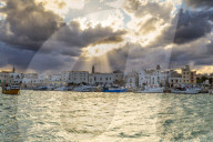 Old town illuminated by sun rays that filters between clouds. Monopoli, Apulia, Italy, Europe.
