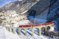 Bernina Express passes over the helical viaduct of Brusio. Valposchiavo, Canton of Graubunden, Switzerland, Europe.