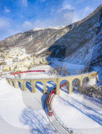 Bernina Express passes under the helical viaduct of Brusio. Valposchiavo, Canton of Graubunden, Switzerland, Europe.
