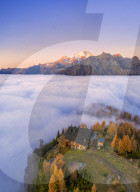 Fog covers the Valmalenco with the Mount Disgrazia illuminated by sunrise and the Motta hut. Valtellina, Lombardy, Italy.