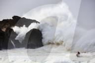 Jet scooter in front of big waves crashing into rocks at the beach