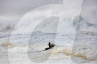Jet scooter in front of big waves crashing into rocks at the beach