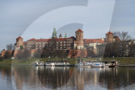 View to Wawel castle with restaurant boats moored on Wista River in riverside park. Krakow, Poland,