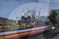 LON 86 Long exposure of passenger train travelling towards Battersea Power Station, London