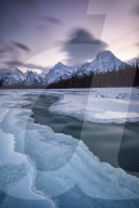 The Athabasca River in winter with mountain backdrop, Alberta, Canada.