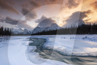 Athabasca River in winter with mountain backdrop, Alberta, Canada.