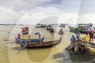 Sampans and other small boats in Sittwe harbour, with people standing on the shore