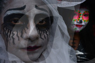 People in costume participating in comparsas or street dances during the Day of The Dead Celebration.