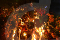 Zapotec woman holding candle among graves adorned with marigolds