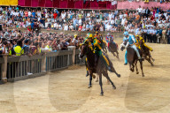 Jockeys in colourful outfits representing their respective neighbourhoods at full pelt at the Palio, a bareback horserace.