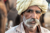 Close-up head shot portrait of bearded camel trader with cream turban, Pushkar Camel Fair, Pushkar, Rajasthan, India