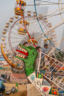 Fairgoers wait for a a swinging gondola to start with two Ferris wheels in the background, Pushkar Fair.