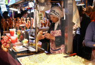Muslim woman selling food at stall in Huajue night market, Xi‚Äôan, Shaanxi, China