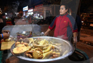 Woman selling cooked meats from rickshaw stall in Turfan night market, Xinjiang, China
