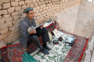 Uyghur man playing a Rawap, traditional Uyghur lute, in Gaochang, ruined Silk Road city, Xinjiang, China