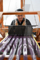 Uyghur woman at loom weaving tie dyed silk thread into traditional cloth, Jiya, Xinjiang, China
