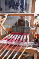 Uyghur man at loom weaving tie dyed silk thread into traditional cloth, Jiya, Xinjiang, China