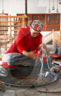 Uyghur woman spinning silk thread from cocoons in traditional silk workshop, Jiya, Xinjiang, China