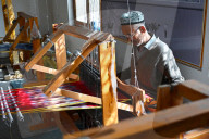 Uyghur man at loom weaving tie dyed silk thread into traditional cloth, Jiya, Xinjiang, China