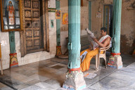 Hindu priest reading the daily newspaper at an old backstreet temple in the palls (alleyways) of old Ahmedabad, Gujarat, India