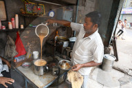 Busy chaiwallah pouring tea at a chai stall in the palls (alleyways) of old Ahmedabad, Gujarat, India