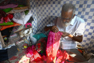 Tailor hand embroidering gold thread onto fabric in his tiny booth in the palls (alleyways) of old Ahmedabad, Gujarat, India