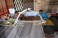 Two men weaving patterned wool carpet on a hand built traditional wooden loom, Bhuj, Gujarat, India