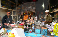 Village general stores, Muslim shopkeeper measuring honey for a customer, Dasada village, Gujarat, India
