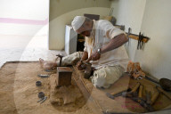 Muslim bell maker beating copper into shape to make bells by hand for cattle or for the home, Nirona village, Gujarat, India