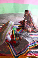 Women embroidering traditional tribal quilts in their bhunga, circular village mud house, Bhirindiara, Kutch, Gujarat, India