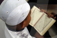 Muslim boy learning Quran at Islamic school. Kufi hat.