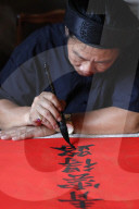 The Temple of Literature. Man doing Traditional Chinese writing in ink using a brush. Hanoi. Vietnam.