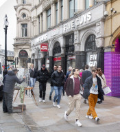 A painter paints a picture of Five Guys in Piccadilly Circus.
