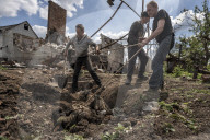 NEWS - Ukraine-Krieg: Männer ziehen die Leiche eines toten russischen Soldaten aus einem Hinterhof in Malaya Rohan