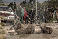 NEWS - Ukraine-Krieg: Männer ziehen die Leiche eines toten russischen Soldaten aus einem Hinterhof in Malaya Rohan