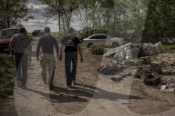 NEWS - Ukraine-Krieg: Männer ziehen die Leiche eines toten russischen Soldaten aus einem Hinterhof in Malaya Rohan