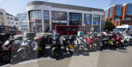 Mopeds are lined up along Wimbledon Broadway with delivery drivers waiting