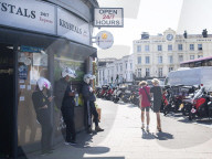 Mopeds are lined up along Wimbledon Broadway with delivery drivers waiting