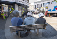 Mopeds are lined up along Wimbledon Broadway with delivery drivers waiting