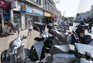 Mopeds are lined up along Wimbledon Broadway with delivery drivers waiting