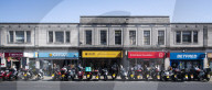 Mopeds are lined up along Wimbledon Broadway with delivery drivers waiting