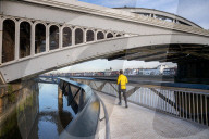 Public enjoy the views of the river Thames from footbridge that goes under the grade II listed Barnes Railway Bridge in south-west London.