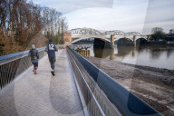 Public enjoy the views of the river Thames from footbridge that goes under the grade II listed Barnes Railway Bridge in south-west London.