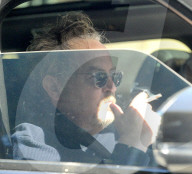 Matthew Perry looks disheveled and solemn as he puffs on a cigarette whilst being chauffeur driven to a tennis club on the afternoon of January 25, 2023. 