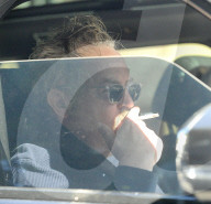 Matthew Perry looks disheveled and solemn as he puffs on a cigarette whilst being chauffeur driven to a tennis club on the afternoon of January 25, 2023. 