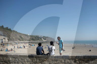 Beachgoers Enjoy Sunny Sands in Folkestone, UK.