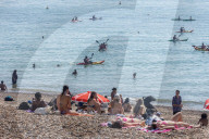 Sunbathers and swimmers on Brighton beach East Sussex, UK.
